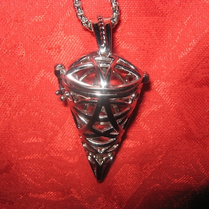 May include: A silver pendant with a geometric, cage-like design. The pendant is shaped like a cone and has a small opening at the top. The pendant is hanging from a silver chain.