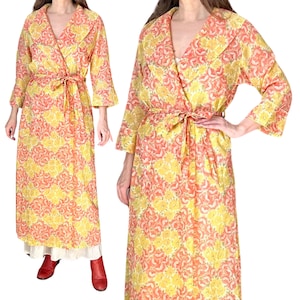May include: A long, floral-patterned robe in yellow and peach. The robe features a shawl collar, three-quarter sleeves, and a matching tie belt. The fabric has a repeating floral design. The robe is floor-length.