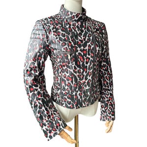 May include: A black, red, and white leopard print jacket with a stand-up collar and an asymmetrical zipper. The jacket has a quilted shoulder detail and a small zippered pocket on the chest. The sleeves are long and fitted.