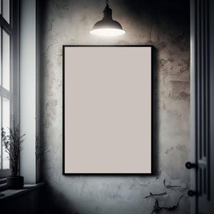 Peut inclure: Un cadre blanc vide avec une bordure noire est accroché à un mur gris texturé. Un luminaire noir est suspendu au-dessus du cadre.