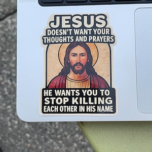 May include: A sticker featuring an image of Jesus with the text "JESUS DOESN'T WANT YOUR THOUGHTS AND PRAYERS" above the image. Below the image, the text reads "HE WANTS YOU TO STOP KILLING EACH OTHER IN HIS NAME."
