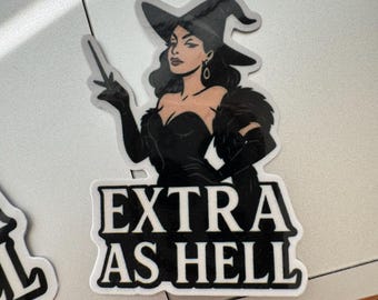 May include: Black and white sticker featuring a witch with a hat, gloves, and a wand. The sticker has the text "EXTRA AS HELL" in a bold, blocky font. The witch is depicted with dark hair and a stern expression.