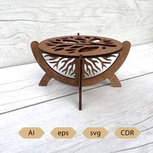 May include: A wooden decorative box with a tree design cut into the top and sides. The box is brown with a white interior and has a three-legged stand. The image also includes the text "Ai", "eps", "svg", and "CDR".