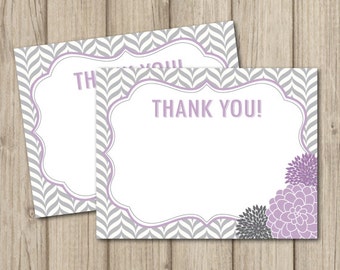 May include: Two thank you cards with a gray and white chevron pattern. The cards have a purple border and a purple floral design in the bottom right corner. The text "THANK YOU!" is printed in purple on the card.