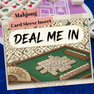 May include: A Mahjong card sleeve insert with the text "DEAL ME IN" in large black letters. The illustration depicts a Mahjong game in progress, with tiles arranged on a green table. A fan is visible in the corner.