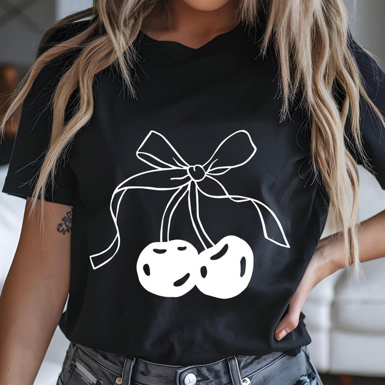 May include: Black t-shirt featuring a white outline of two cherries tied with a bow. The graphic is centered on the shirt. The shirt has short sleeves and a crew neck.