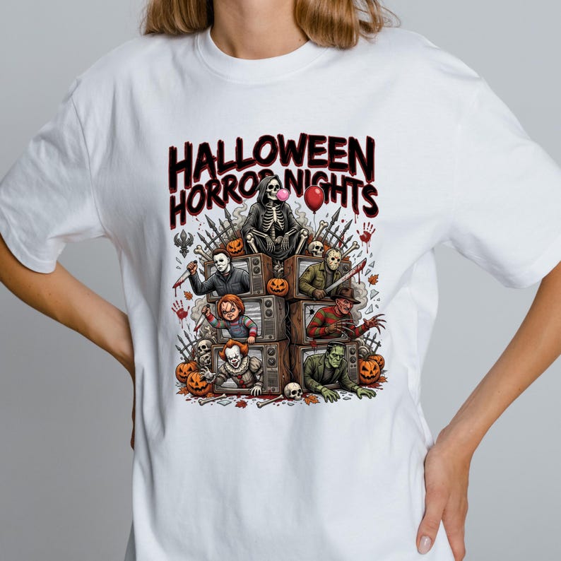 May include: A white t-shirt featuring a graphic print with the text "HALLOWEEN HORROR NIGHTS" above a stack of vintage televisions. Each screen displays a different horror character, surrounded by pumpkins, skulls, and a red balloon.