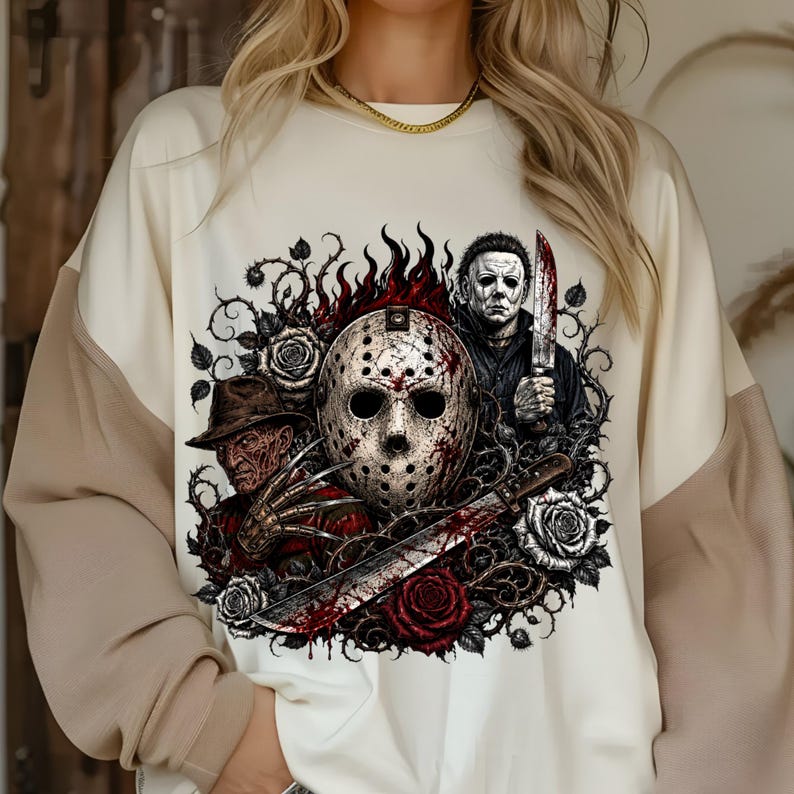 May include: A cream-colored sweatshirt featuring a graphic print of three horror movie characters: a hockey mask, a man in a fedora with clawed gloves, and a man holding a knife. The design includes red roses, thorny vines, and flames.