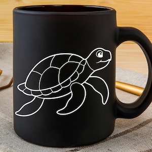 May include: Black ceramic mug featuring a white outline of a sea turtle. The turtle design is on the front of the mug, with the handle on the right side. The mug is sitting on a neutral-colored surface.