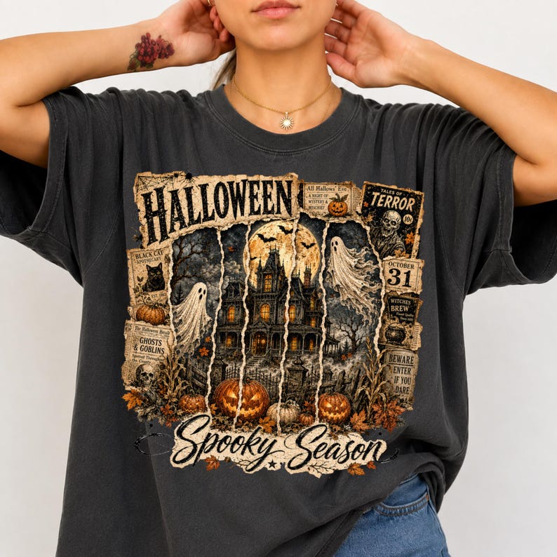 May include: A charcoal gray t-shirt featuring a graphic print with the text "HALLOWEEN" and "Spooky Season". The design includes a haunted house, ghosts, pumpkins, a black cat, a skeleton, and vintage-style newspaper clippings with "TALES OF TERROR".