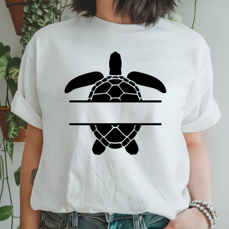 May include: White t-shirt featuring a black turtle design. The turtle is split into two halves with a horizontal blank space in the middle. The turtle's shell has a geometric pattern.