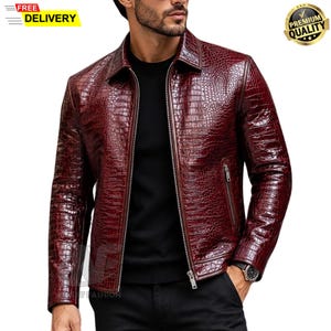 Peut inclure: Une veste bordeaux profond avec un motif texturé en peau de crocodile, un col classique et une fermeture éclair métallique argentée. Le vêtement comprend deux poches latérales zippées et des manches longues, porté sur un t-shirt noir.