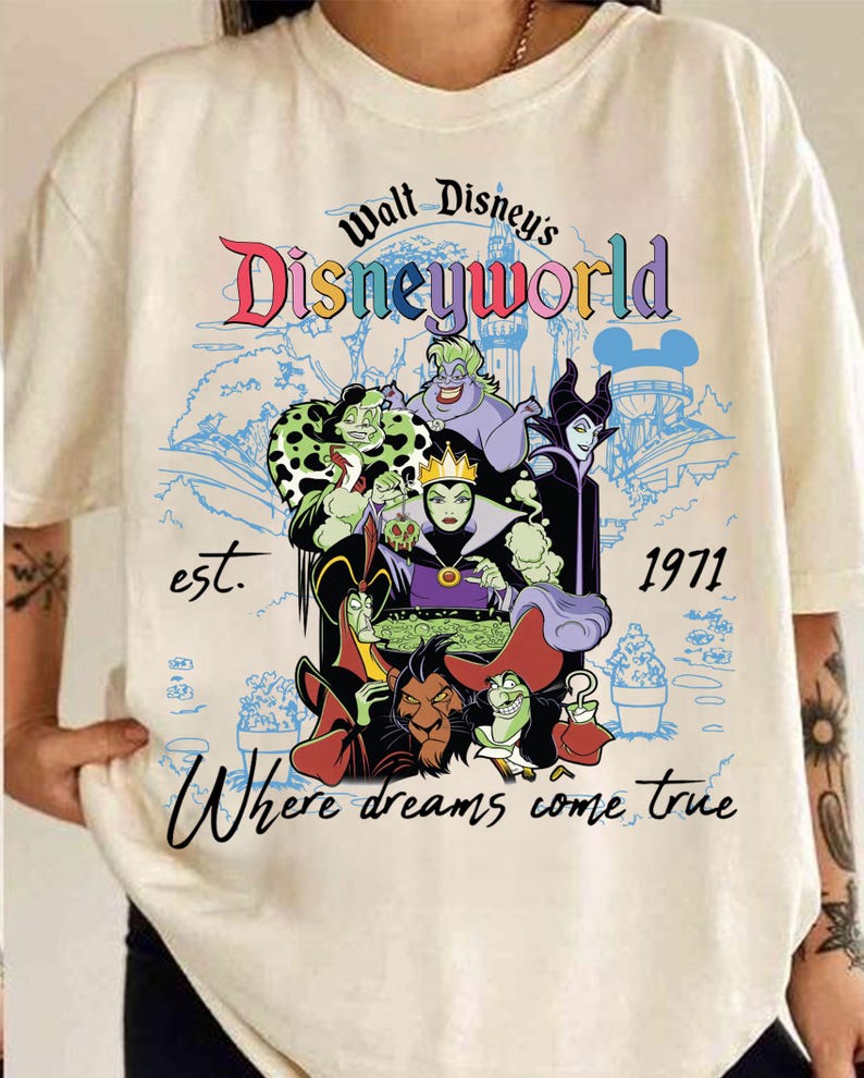 May include: Cream-coloured t-shirt with a colourful graphic of Disney villains. The design includes the text "Walt Disney's Disneyworld" and "Where dreams come true", with the year "1971". The graphic showcases various animated characters.