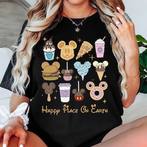 Może przedstawiać: Czarny t-shirt z kolorowymi ilustracjami różnych produktów spożywczych, w tym lodów, pizzy i burgera, ułożonych w siatkę. Fraza "Happy Place On Earth" jest wydrukowana złotymi literami pod ikonami jedzenia.