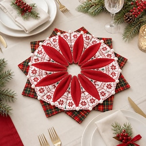 Puede incluir: Un mantel individual de tela en forma de estrella con un patrón de copos de nieve rojos y blancos, detalles en forma de pétalos rojos y pequeñas cuentas blancas en los bordes, sobre un mantel individual cuadrado de cuadros verdes y rojos.