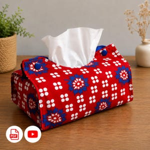 以下が含まれることがあります： 鮮やかな赤色の布製長方形ティッシュボックスカバー。青い花柄と小さな白い円が繰り返される模様が特徴です。カバーの上部フラップは青いボタンで留められており、白いティッシュペーパーがセットされています。