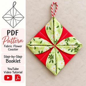 May include: A square fabric coaster featuring a red base with four folded light green petals decorated with white and dark green flower patterns. A red and white striped loop is attached to the top. Text includes PDF Pattern, Fabric Flower Coaster, Step-by-Step Booklet, and YouTube Video Tutorial.