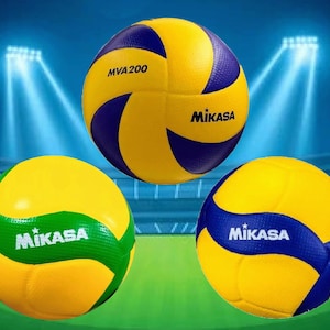 May include: Three volleyballs with yellow, blue, and green panels. The top ball has "MVA200" and "Mikasa" printed on it. The other two balls also have the "Mikasa" logo. The background shows a stadium with bright lights.