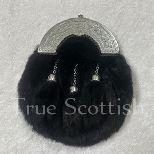 May include: A black fur sporran with a silver cantle featuring Celtic knotwork. The sporran has three silver tassels hanging from the bottom and the text "True Scottish" is printed on the front.