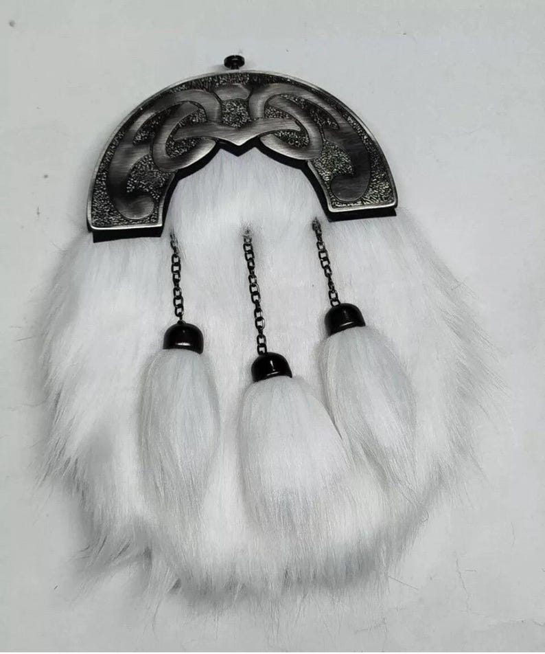 Pu&ograve; includere: Una sporran di pelliccia bianca con un cantle decorativo color argento con un intricato disegno a nodo celtico. Tre nappe bianche pendono dal basso, attaccate da catene nere. Un accessorio scozzese tradizionale.