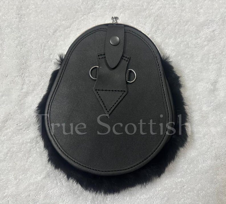 May include: Black leather sporran with a fur trim. The sporran has a flap closure with a button and two metal rings. The text "True Scottish" is visible on the front of the sporran.