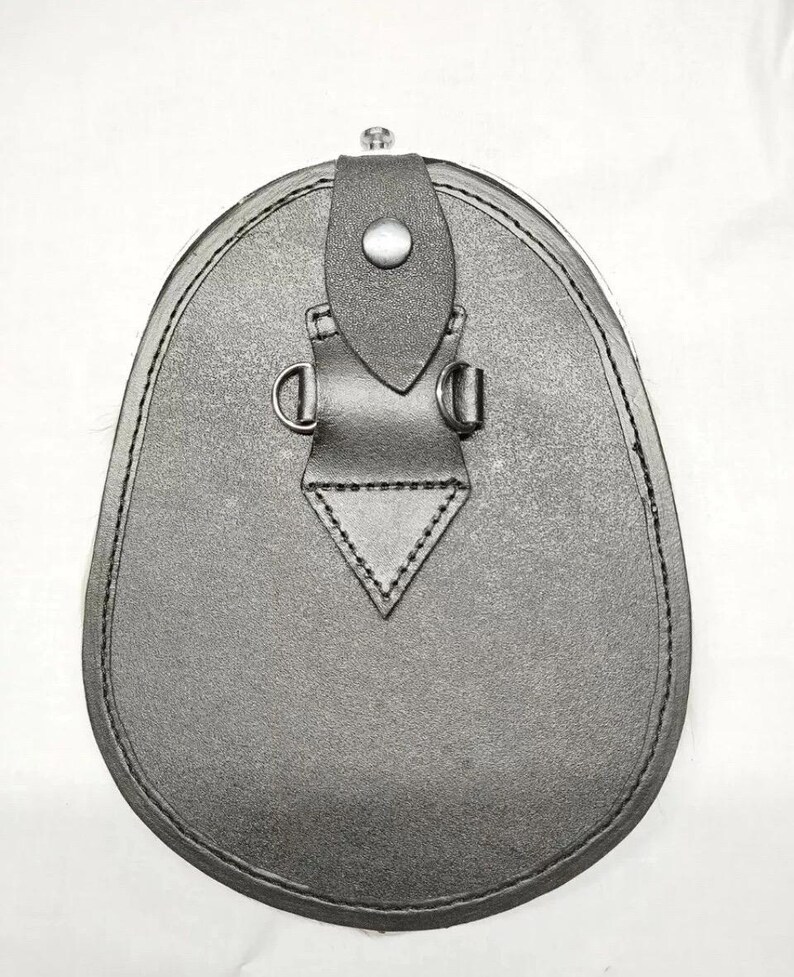 Pu&ograve; includere: Un sporran in pelle nera, una tradizionale borsa scozzese. Ha una base arrotondata e una chiusura a patta con un bottone. Lo sporran presenta cuciture decorative, anelli a D e un design triangolare nella parte inferiore.