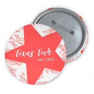May include: A round button with a red star design and the words "Texas Tech est. 1925" in white script. The button has a white background with a red floral pattern and a metal pin back.