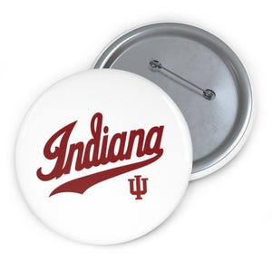 Pode incluir: Botão branco com a palavra "Indiana" em escrita marrom e o símbolo do tridente da Universidade de Indiana. O botão tem uma parte traseira de alfinete de metal.