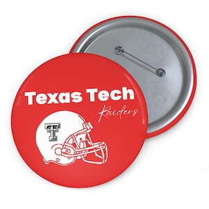 May include: Red button with the words "Texas Tech Raiders" in white. A white graphic of a football helmet is also on the button. The back of the button is silver with a pin.