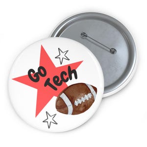 May include: A white button with a red star, the words "Go Tech" in black, and a watercolor football. Two outline stars are also on the button. The back of the button is silver.