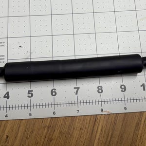 May include: A black cable with silver connectors on each end. The cable is about 10 inches long and is measured on a ruler.