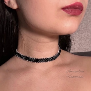 May include: A black beaded choker necklace with a silver border. The choker is worn around the neck. The text "Amaze You Handmade" is visible in the lower right corner.