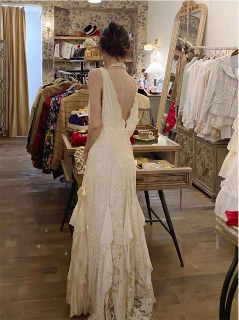 May include: A white lace dress with a low back and a ruffled skirt.