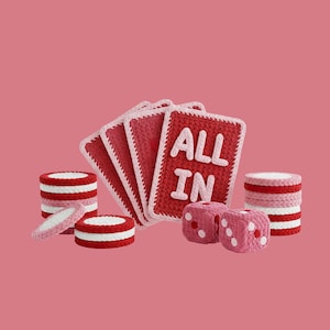 May include: A set of handmade crochet poker game pieces, including playing cards with "ALL IN" text, dice, and poker chips. The pieces are mainly red, white, and pink, set against a pink background.