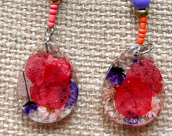 Fantastical. Dangle earrings featuring orange and purple colors are a nod to the seventies. They will surely brighten your day.
