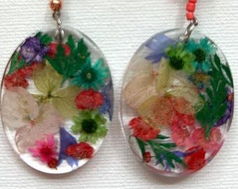 Salient. Green and orange beads enhance the plant material in these beautiful earrings. Pressed flowers have been encased in clear resin