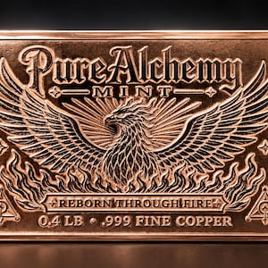 May include: A rectangular copper bar featuring an embossed phoenix rising from flames. The text reads Pure Alchemy Mint, Reborn Through Fire, 0.4 LB, and .999 Fine Copper. Two small triangular symbols are located in the bottom corners.