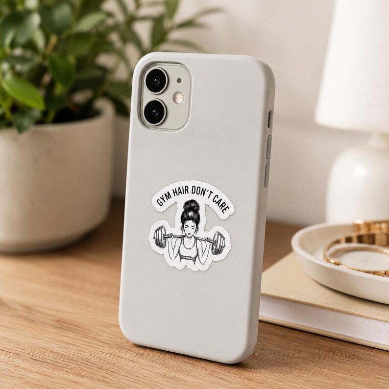 A white smartphone in a clean white case with a weightlifting sticker applied to the back. This tech mockup highlights the laptop decals and phone sticker use cases for this powerlifting decals for women set.