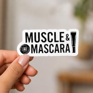 A hand with manicured nails holding a white sticker that says MUSCLE & MASCARA with small weight icons. This sticker highlights the intersection of femininity and strength in the powerlifting decals for women set.