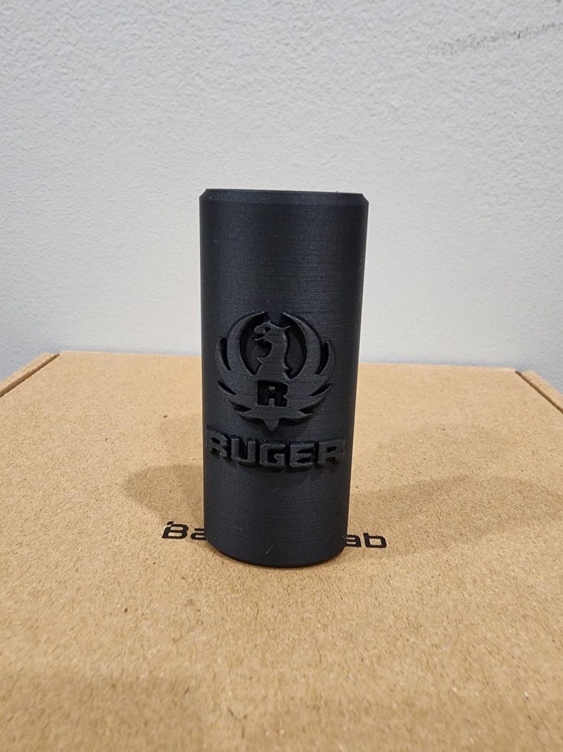 May include: A black cylindrical object with the Ruger logo and the word "RUGER" embossed on the side.