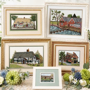 May include: Five framed cross-stitch pictures of quaint cottages and landscapes. The frames are in various styles, including gold, white, and wood tones. The artwork features detailed needlework of thatched roofs, brick buildings, and lush greenery.