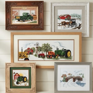Puede incluir: Una colección de obras de arte en punto de cruz enmarcadas que representan escenas rurales. Las piezas presentan tractores, graneros y paisajes invernales. Los marcos varían en estilo, incluyendo madera oscura ornamentada y madera clara simple.