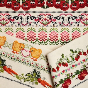 Op de afbeelding: Close-up van verschillende kruissteekpatronen met verschillende ontwerpen. De patronen omvatten lachende rode tomaten, zwart-witte koeien met harten, roze ananassen, gele kuikens, wortelen en aardbeien. De ontwerpen staan op een crèmekleurige stof.