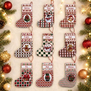 Könnte beinhalten: Neun personalisierte Weihnachtsstrümpfe mit Namen, jeder mit einem einzigartigen Design. Die Strümpfe sind rot, grün und weiß, mit festlichen Motiven wie Schneemännern, Teddybären und Weihnachtsbäumen. Jeder Strumpf ist etwa 15 cm hoch.