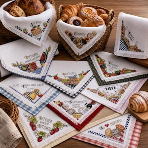 Peut inclure: Ensemble de serviettes de cuisine brodées avec des motifs culinaires et des inscriptions comme "Cookies!" et "Kitchen Sweet Kitchen". Les serviettes présentent des motifs au point de croix et des bordures décoratives. Des paniers de pain et de pâtisseries sont visibles en arrière-plan.