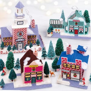 Peut inclure: Ensemble d'ornements de village de Noël faits à la main. L'ensemble comprend un palais de justice, une boutique de fleurs, un salon de thé et une caserne de pompiers, tous fabriqués avec du fil rouge, bleu et rose. Des arbres miniatures et des accents de neige complètent la scène festive.