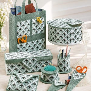 May include: A collection of handmade green and white needlepoint craft organizers. Includes a tote bag, a round box, a rectangular box, a pin cushion, a pencil holder, a small square pouch, and a scissor holder. The items feature a geometric pattern.