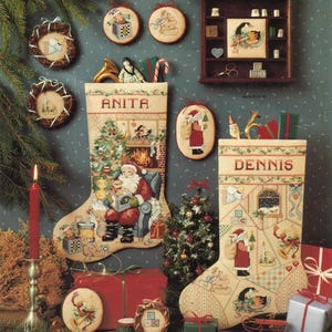 May include: A Christmas-themed arrangement with embroidered stockings, each bearing a name, alongside festive ornaments and a small Christmas tree. The scene is complemented by a lit candle and wrapped presents, evoking a traditional holiday feel.