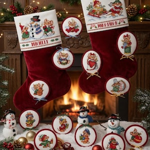 Könnte beinhalten: Zwei rote Weihnachtsstrümpfe mit gestickten Mäusen und den Namen "Michelle" und "Jonathan". Mehrere runde Ornamente mit Mäusemotiven werden zusammen mit Schneemännern und Weihnachtsdekorationen ausgestellt. Die Strümpfe und Ornamente sind festlich.