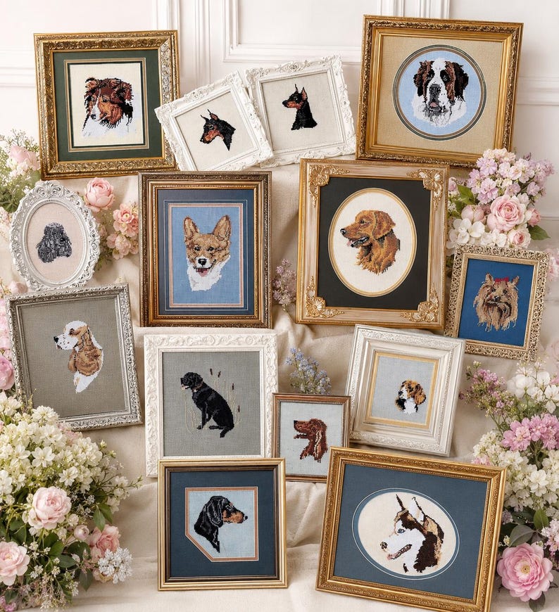 May include: A collection of framed cross-stitch portraits of various dog breeds. The portraits feature detailed depictions of dogs in different poses and colors, set against neutral backgrounds. The frames vary in style, including ornate gold and simple white.